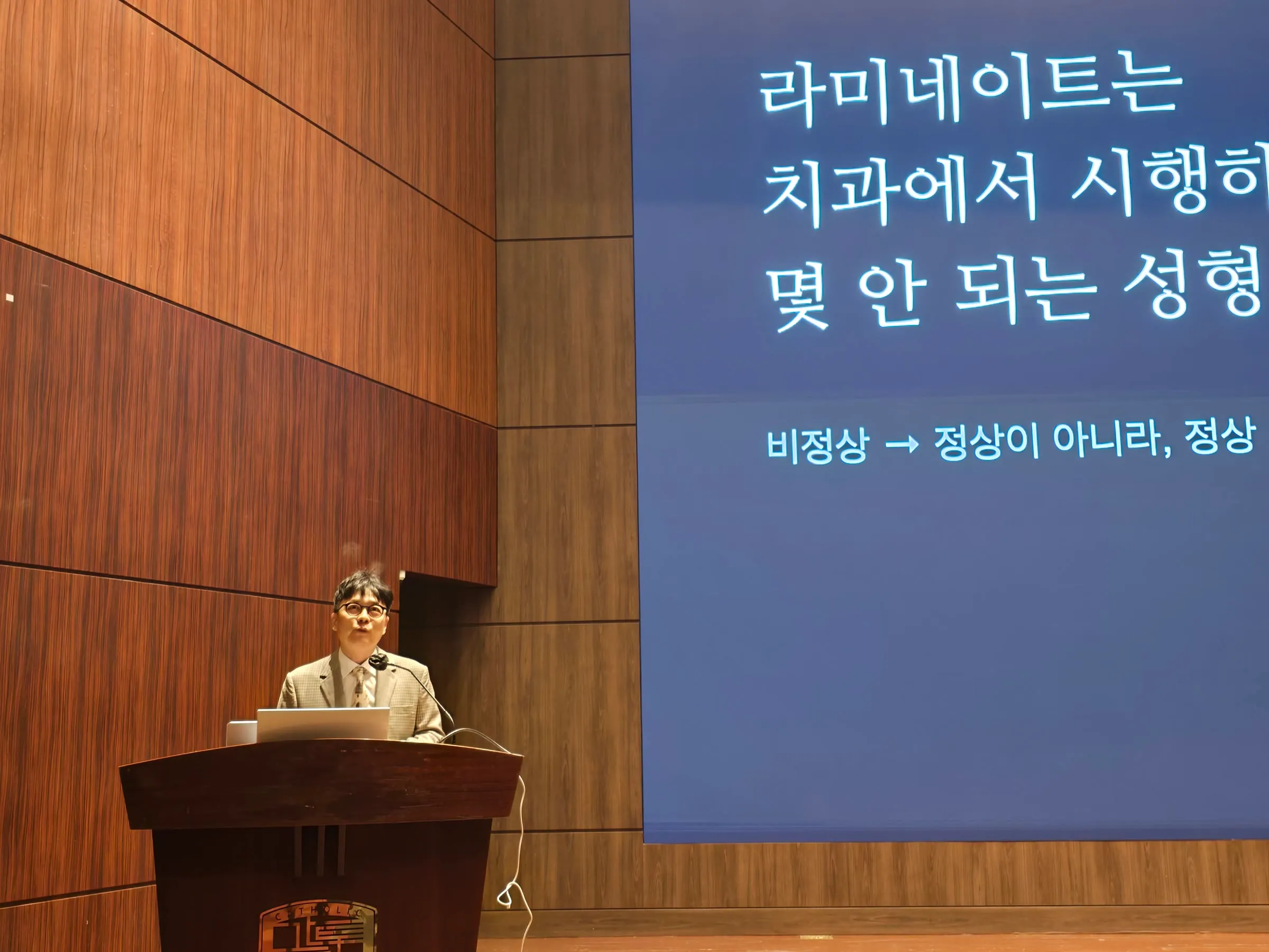 Dr. Park Jonguk lecturing beside a slide on laminate veneers as one of the few cosmetic procedures in dentistry